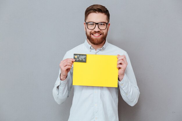 Handsome businessman holding blank paper and debit card