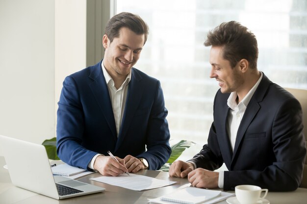 Handsome businessman signing contract with partner