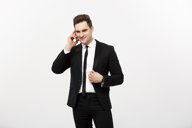 Handsome businessman in suit speaking on the phone over isolated white background.