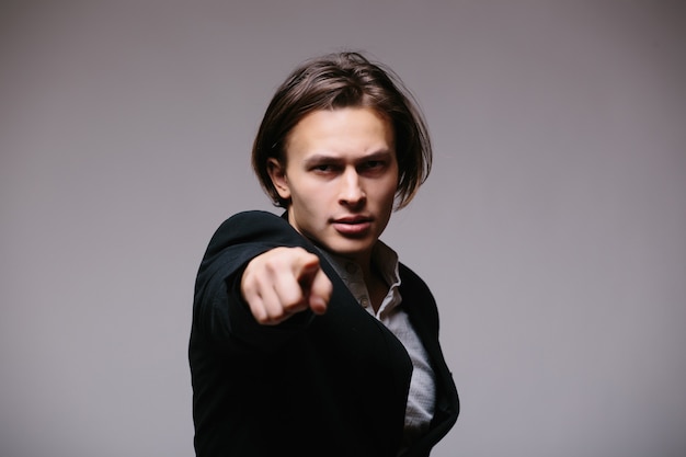 Handsome businessman in sunglasses pointing at front over gray wall