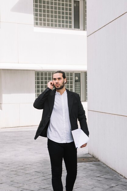 Handsome businessman talking on mobile phone holding documents in the hands