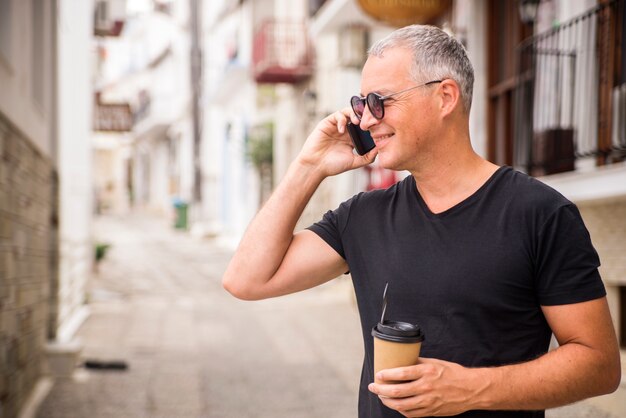 Handsome businessman talking on phone and drinking coffee