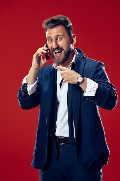 Free photo handsome businessman with mobile phone. happy business man standing isolated on red. beautiful male half-length portrait