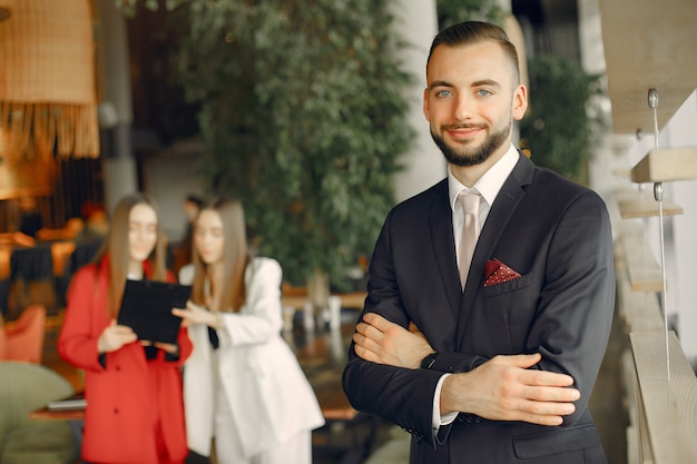 Бесплатное фото Красивый бизнесмен с женщинами, стоя и работает в кафе