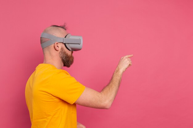 Handsome casual wear men in vr glasses side view pointing to the left text space