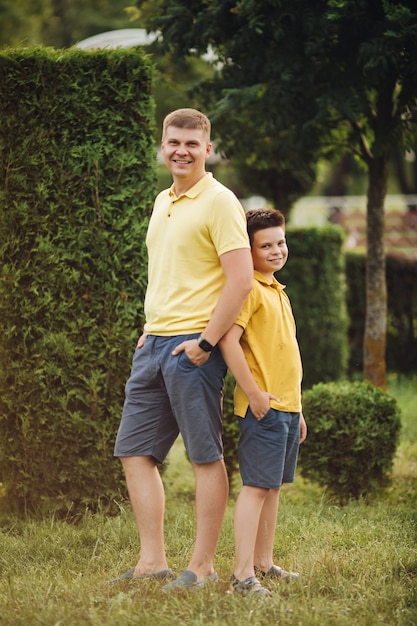 Handsome caucasian father posing for the camera with his little son in the park in summer