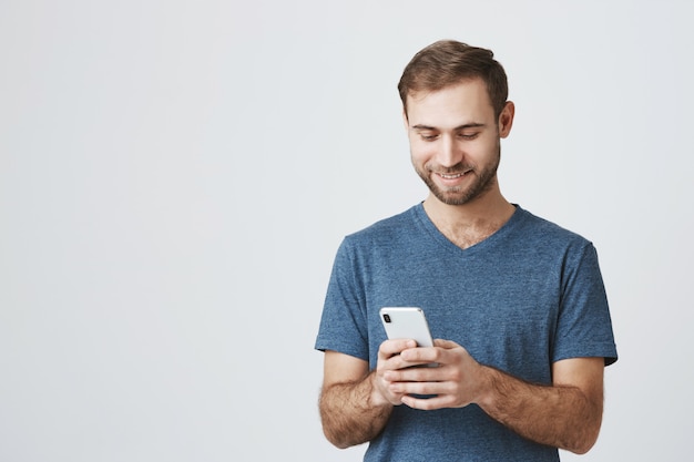 Handsome caucasian guy texting, using mobile phone