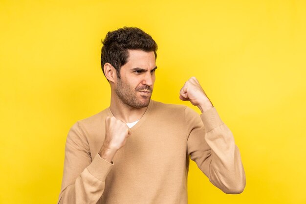 Handsome Caucasian man ready to fight on a yellow background