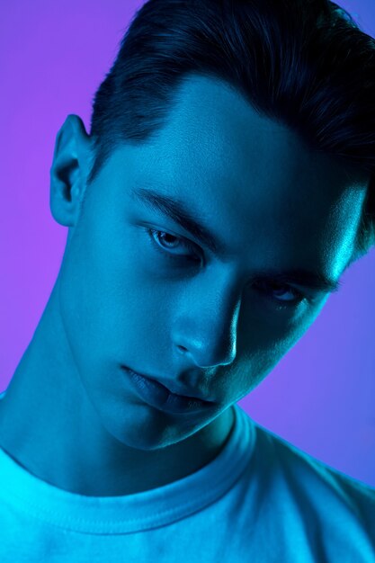 Handsome caucasian man's portrait isolated on purple studio background in neon light, monochrome. Beautiful male model. Concept of human emotions, facial expression, sales, ad, fashion and beauty.