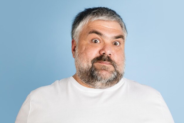 Handsome caucasian plus size male model isolated on blue studio background Concept of inclusion human emotions facial expression