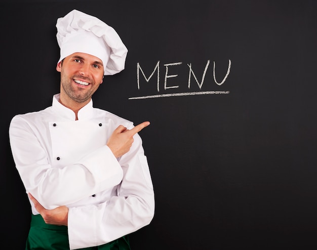 Free photo handsome chef showing menu