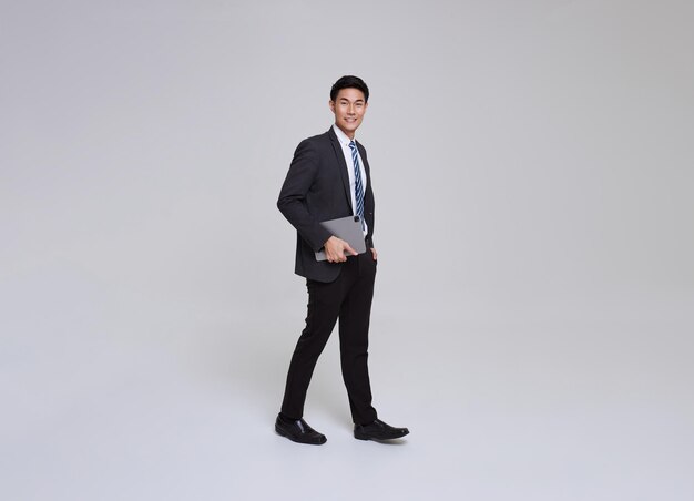 Free Photo handsome confident asian businessman holding digital tablet computer walking