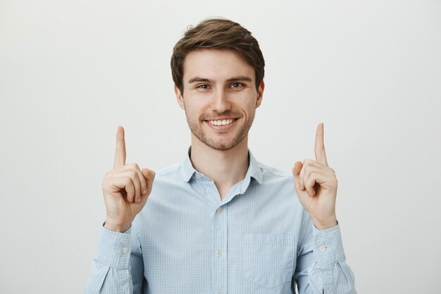 Handsome confident businessman pointing fingers up