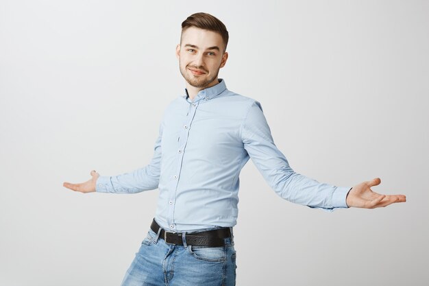 Handsome confident businessman spread hands sideways and smiling proud, show-off his successful business