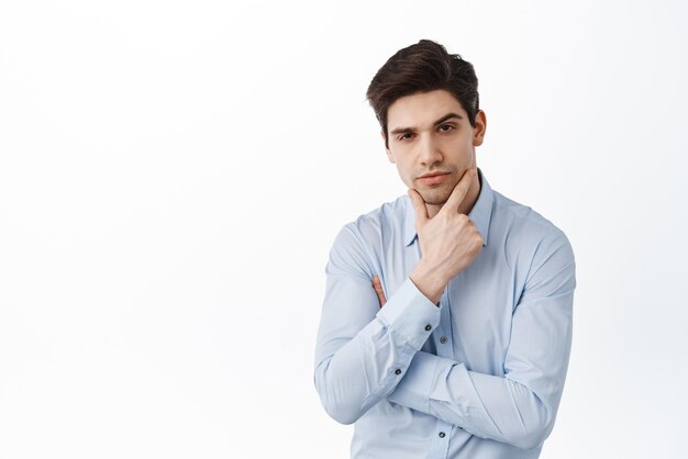 Handsome confident businessman touching jawline and look serious pondering something important thinking standing over white background