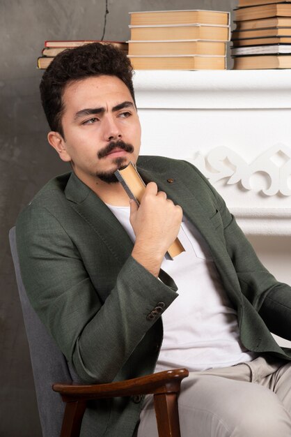 Handsome confident man sitting on chair with book