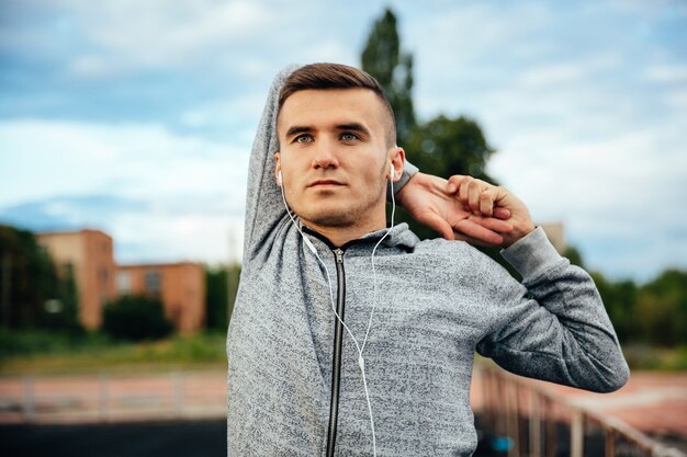 handsome confident young sportsman doing exercises for hands, holding his hand