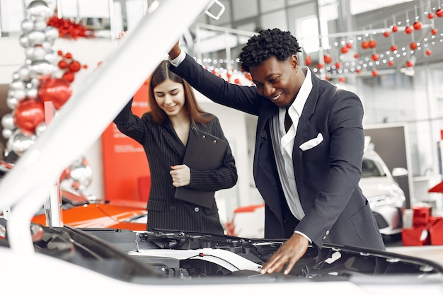 Foto gratuita uomo di colore bello ed elegante in un salone dell'automobile