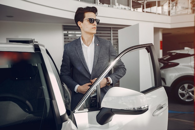 Uomo bello ed elegante in un salone di auto