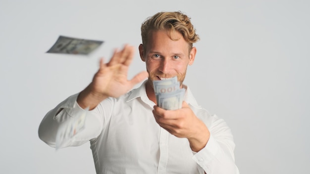 Free photo handsome excited blond bearded businessman happily throwing money into camera isolated on white background successful man