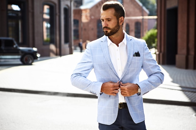 handsome fashion businessman model dressed in elegant blue suit posing on street