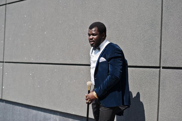 Handsome fashionable african american man in formal wear and bow tie with walking stick