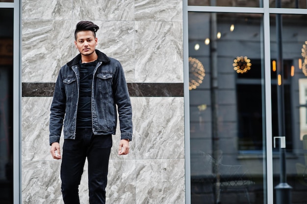 Handsome and fashionable indian man in black jeans jacket posed outdoor