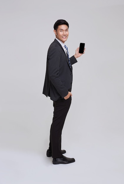 Handsome and friendly face asian businessman smile in formal suit his using smartphone on white background studio shot.