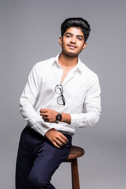 Free photo handsome good looking indian man sitting on a chair and relaxing, isolated for white wall