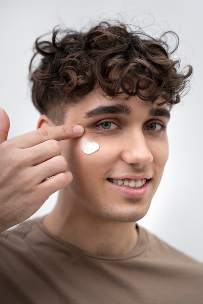 Handsome guy applying lotion on his face