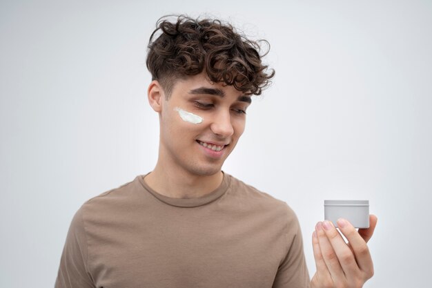 Handsome guy applying lotion on his face