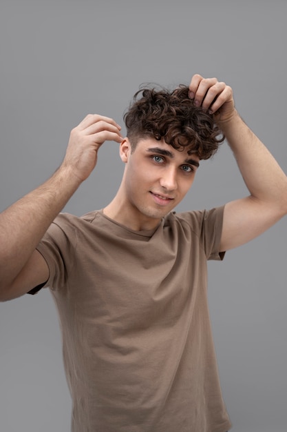 Foto gratuita ragazzo bello che ripara i suoi capelli ricci