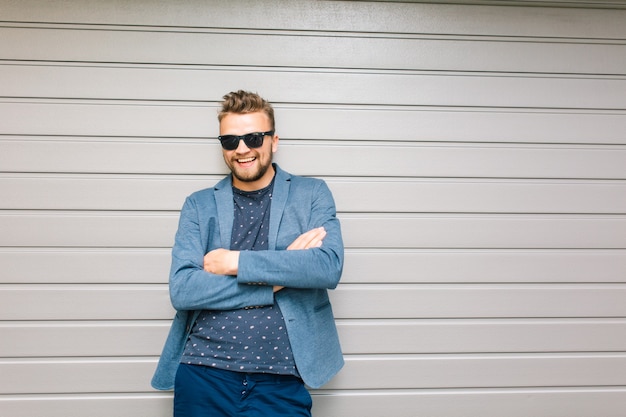 Handsome guy is posing on gray wall