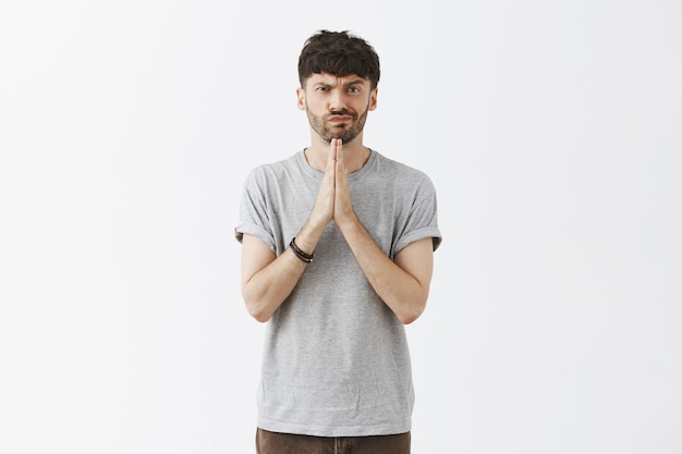 handsome guy posing against the white wall praying