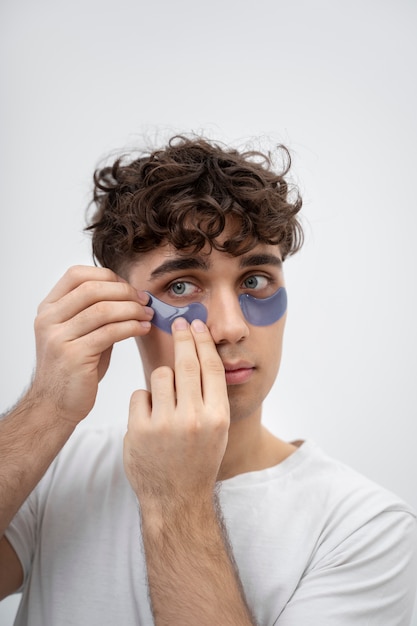 Ragazzo bello che usa i cuscinetti sotto gli occhi