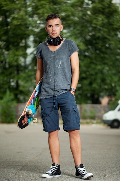 Bel ragazzo con cuffie e skateboard