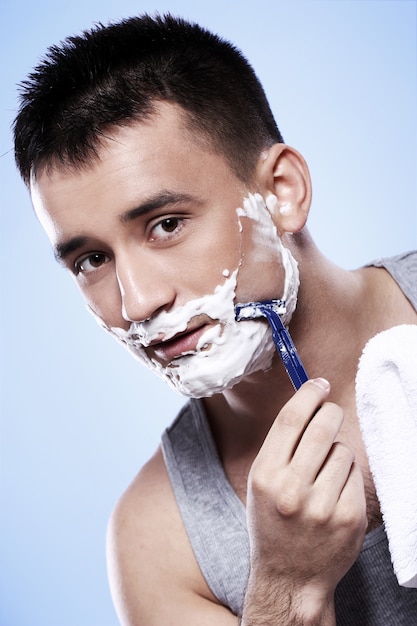 Free photo handsome guy with shaving foam and razor