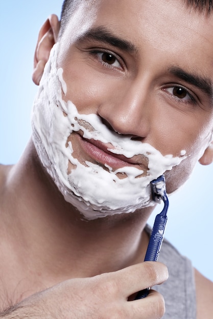 Free photo handsome guy with shaving foam and razor