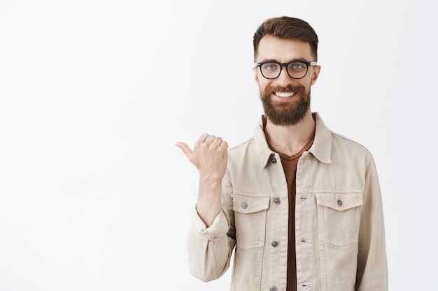 Free photo handsome happy bearded man in glasses posing against the white wall