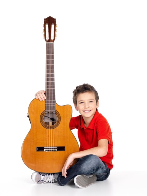 Красивый счастливый мальчик с акустической гитарой, изолированные на белом фоне