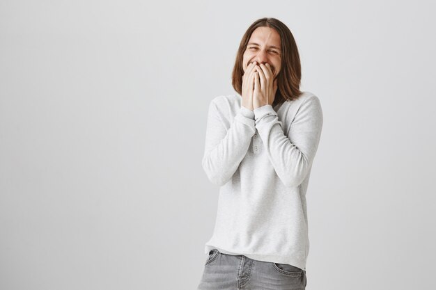 Handsome happy guy laughing over joke, cover mouth