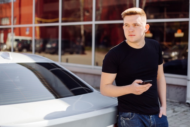 Free photo handsome, happy, young man uses smartphone in car and outdoors