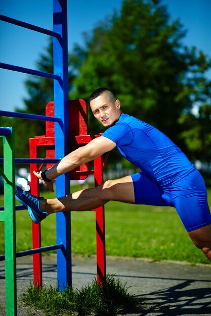 Handsome healthy happy srtong athlete male man exercising at the city park - fitness concepts on a beautiful summer day on horizontal bar