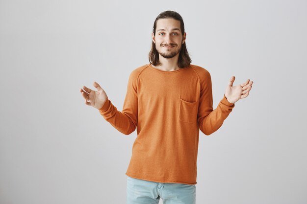 Handsome hipster guy showing big object, smiling happy