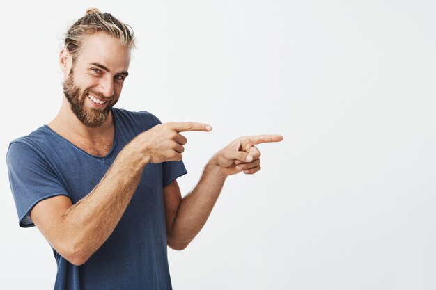 Handsome hipster man pointing with fingers at copyspace