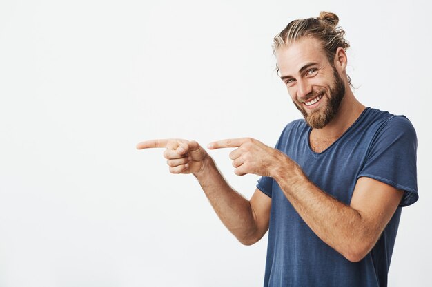 Handsome hipster man pointing with fingers at copyspace