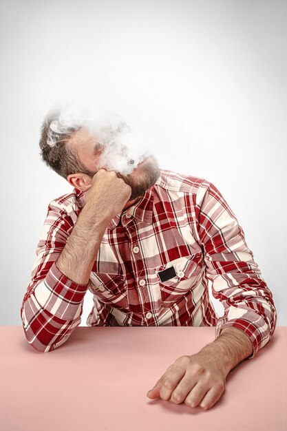 Handsome hipster man smoking cigarette at home.