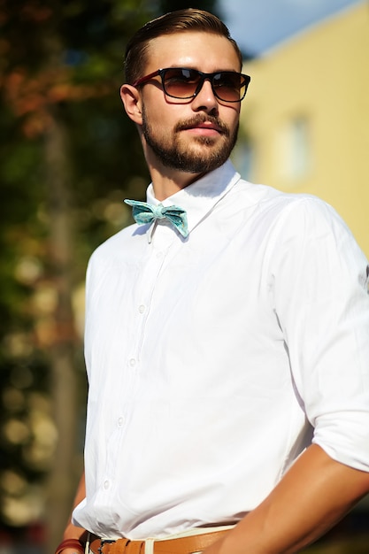 Uomo di modello bello hipster in abiti estivi alla moda in posa in occhiali da sole