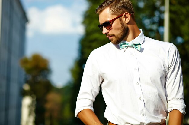 Handsome hipster model man in stylish summer clothes posing in sunglasses