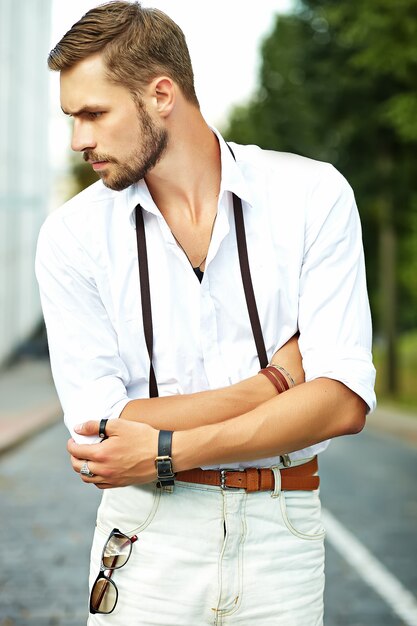 Handsome hipster model man in stylish summer clothes posing